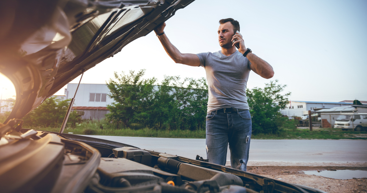 Man on phone with car hood open, experiencing roadside car trouble at sunset need Remanufactured ECM repair