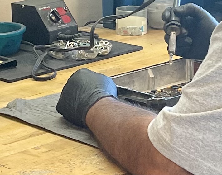 Technician repairing a diesel ECM circuit board as part of a troubleshooting guide at Diesel ECM Technology
